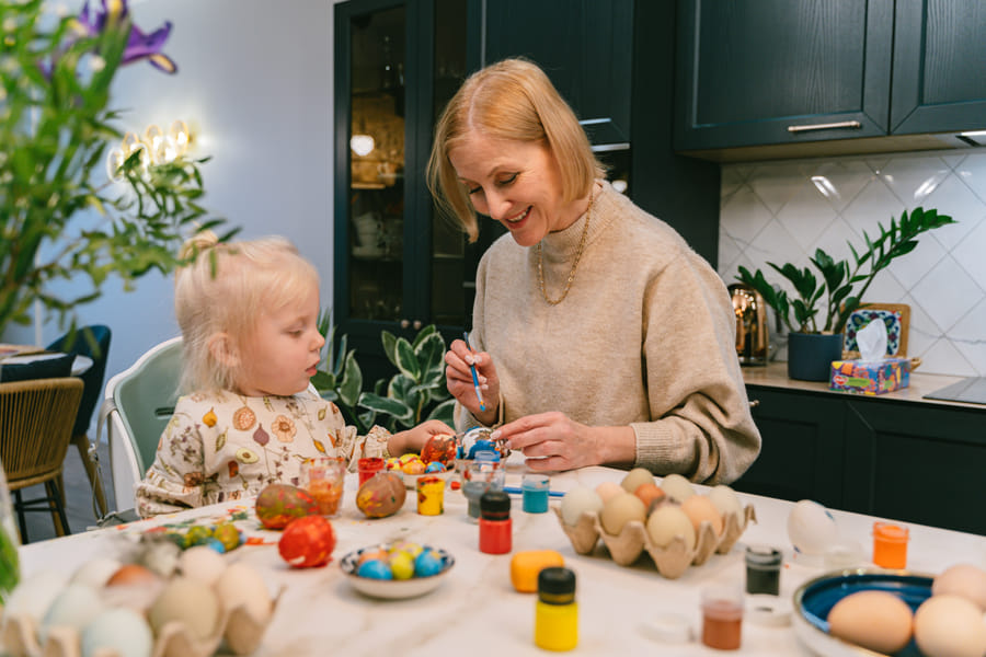 Preschooler joyfully painting an Easter egg on canvas for a creative craft project